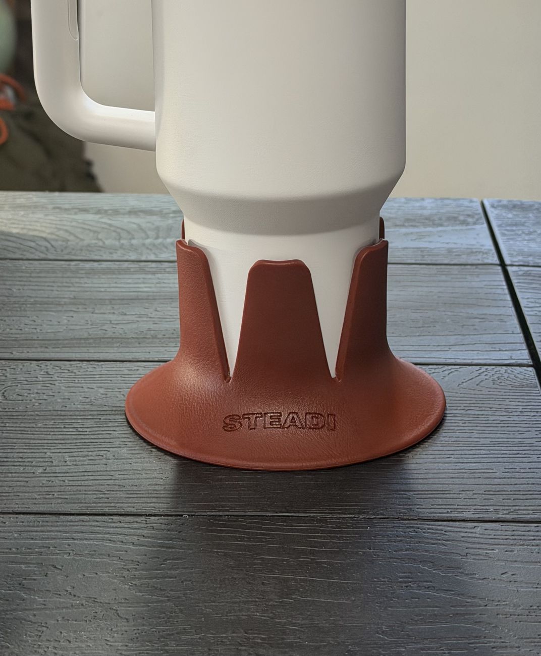 A tumbler seated in a terracotta Steadi on a table, with daylight from a window behind it.