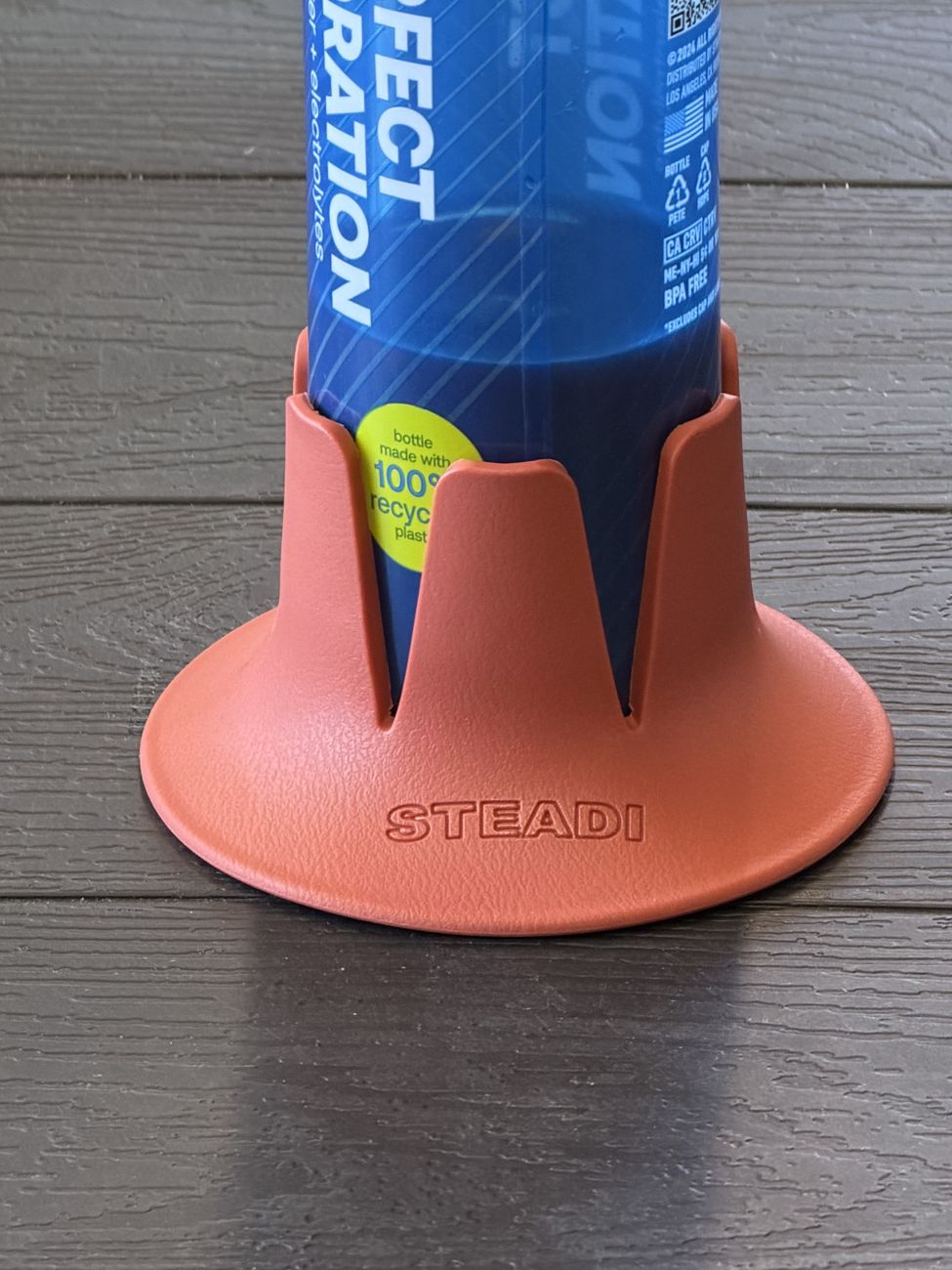 A water bottle seated in a terracotta Steadi on a table.