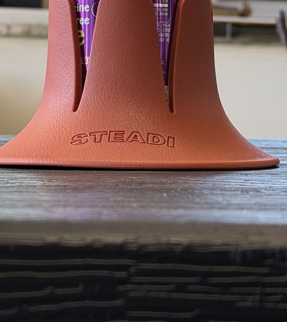 A sage Steadi standing alone on the edge of a table in a room.